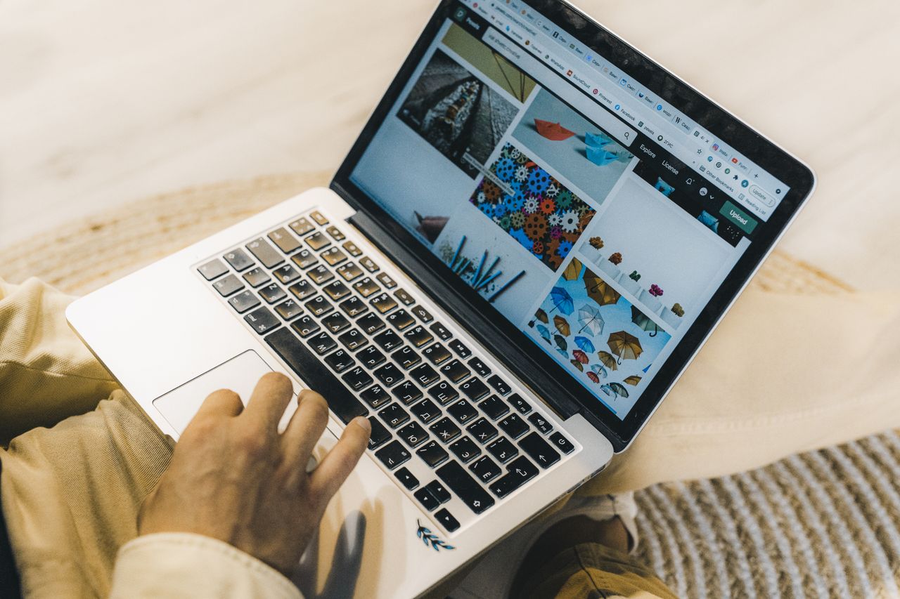 A person working on a laptop while browsing stock photo websites. Freelancing in a comfortable setting.