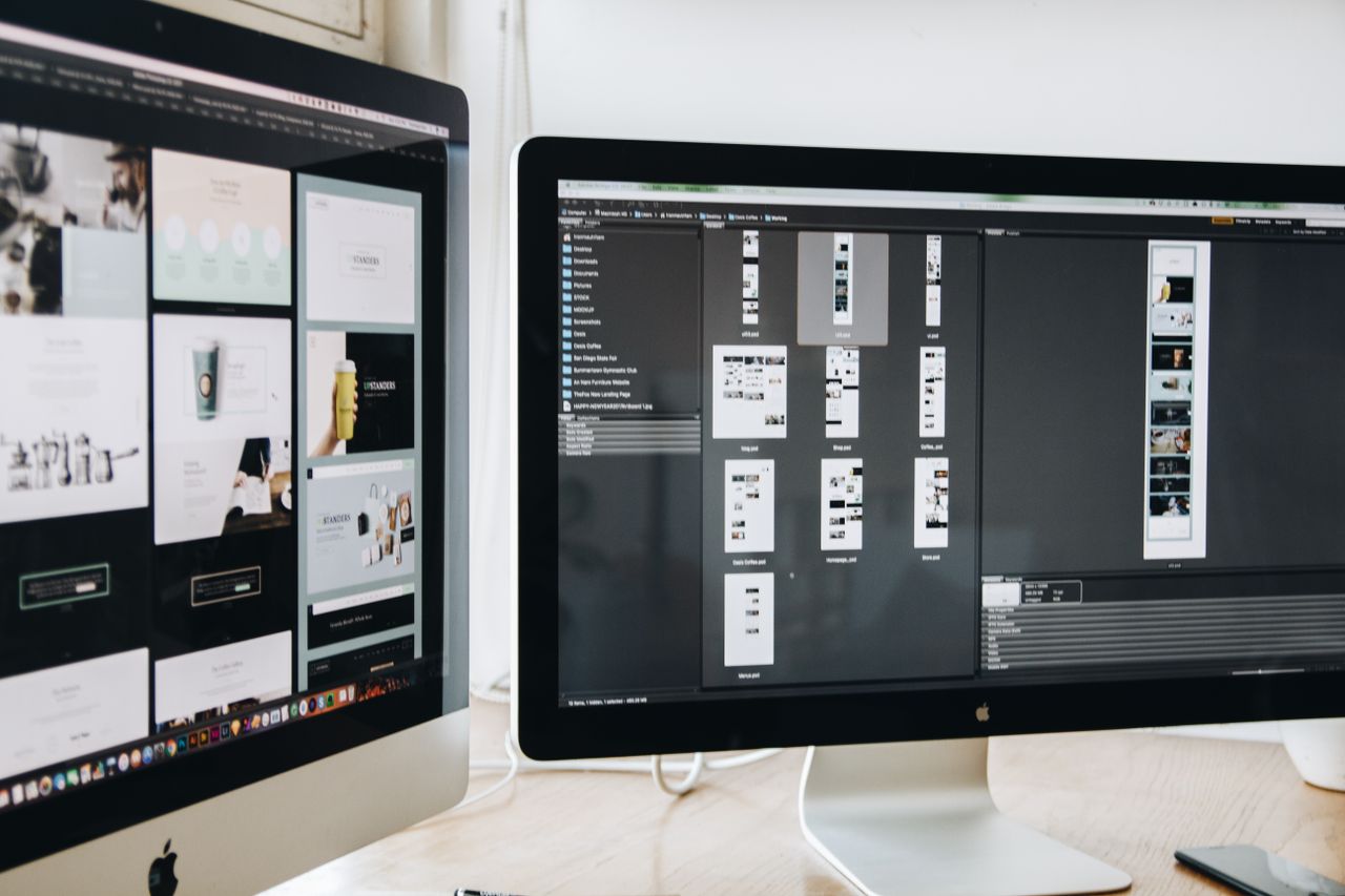 Un espace de travail moderne avec deux écrans d’ordinateur montrant des projets de conception web, mettant en avant la technologie et la productivité.
